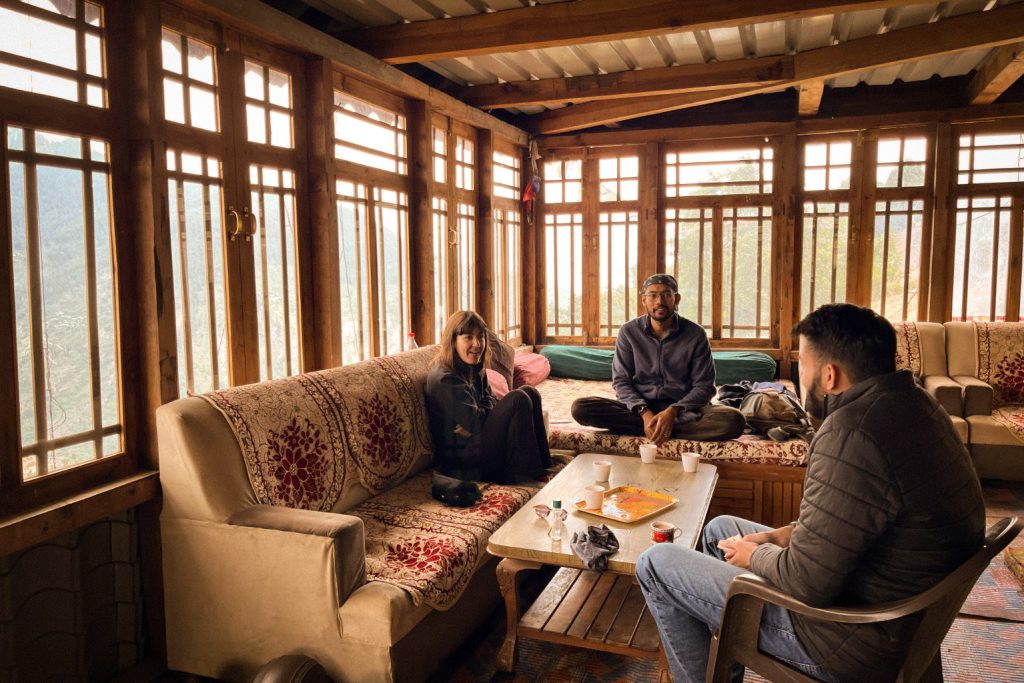 Guests share tea and conversation in a cozy wood-paneled room overlooking the mountains.