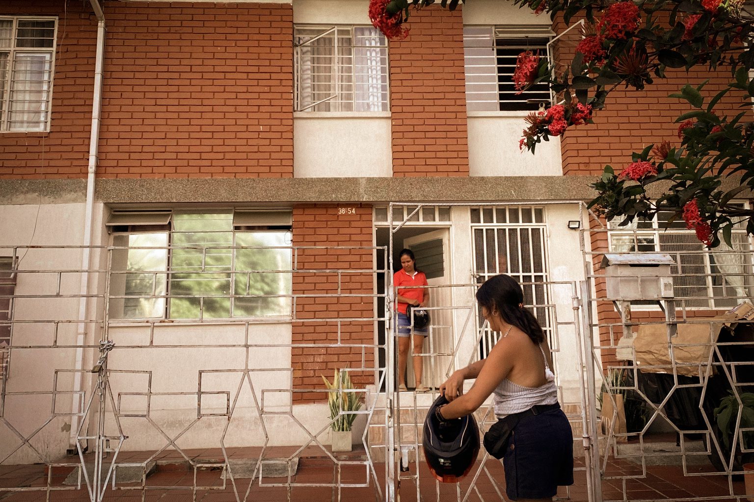 A traveler is welcomed at the door by a local, motorbike helmet in hand.