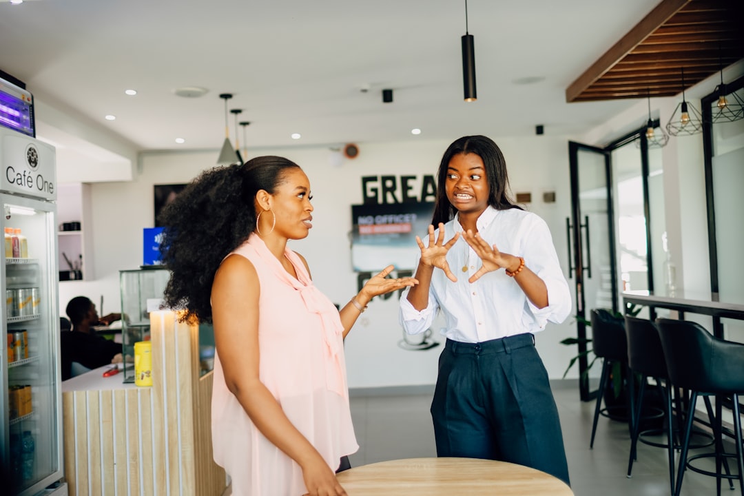 Two women mid-conversation in a cafe, one gesturing while she talks