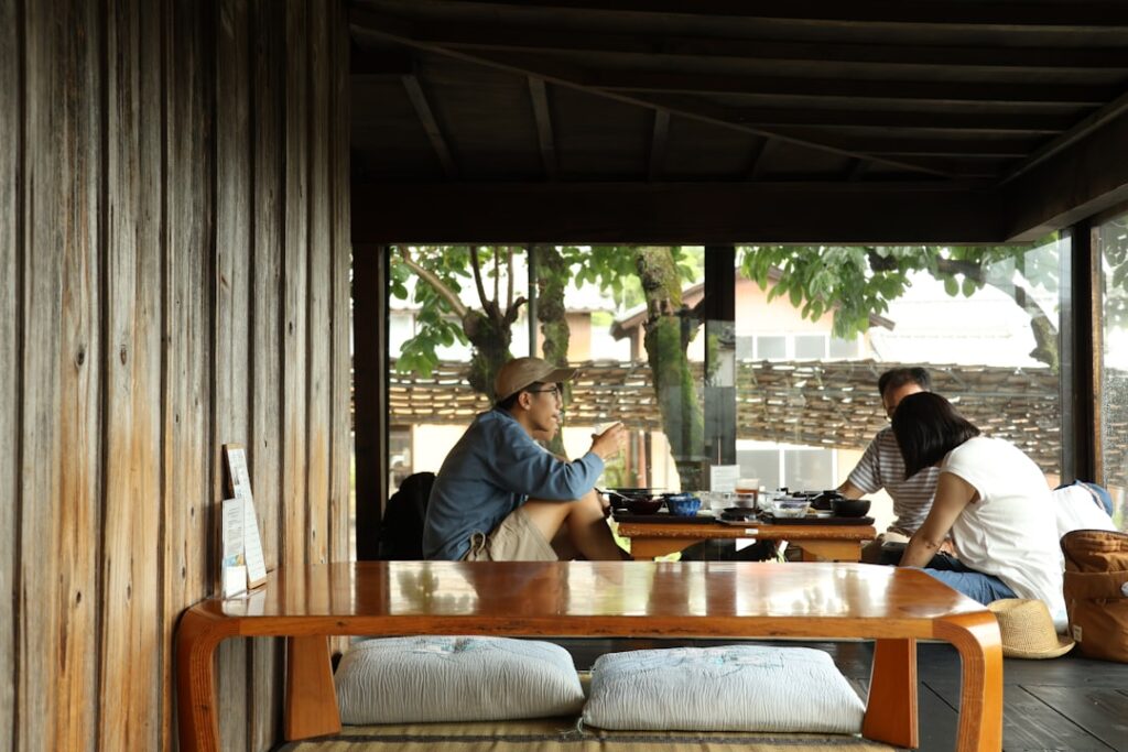 A small group of people sitting together around a table on a wooden porch, sharing food and conversation