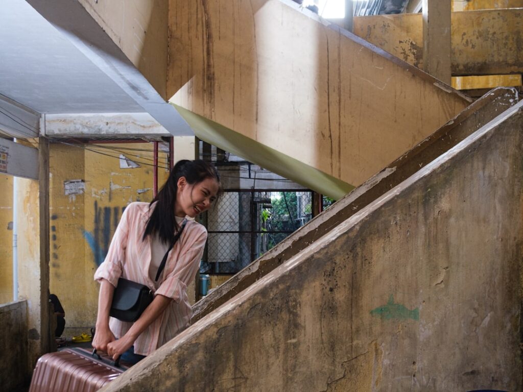A woman pulls her luggage up old concrete stairs after moving abroad