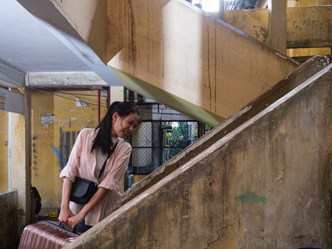 A woman pulls her luggage up old concrete stairs